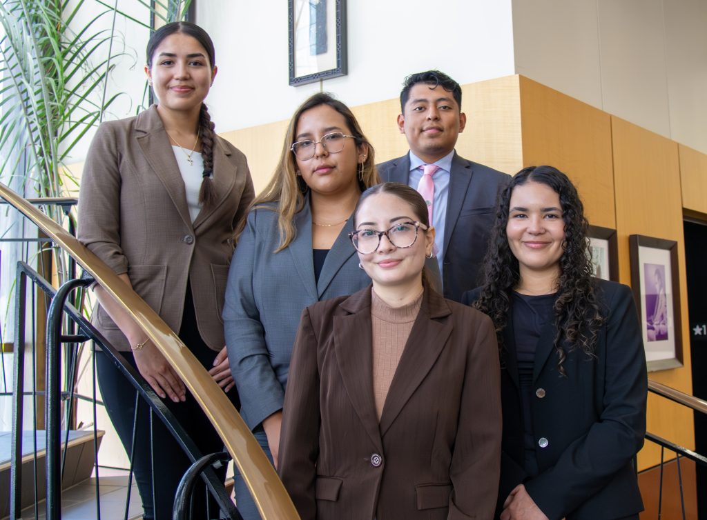 A group of students dressed professionally and standing on a spiral staircase