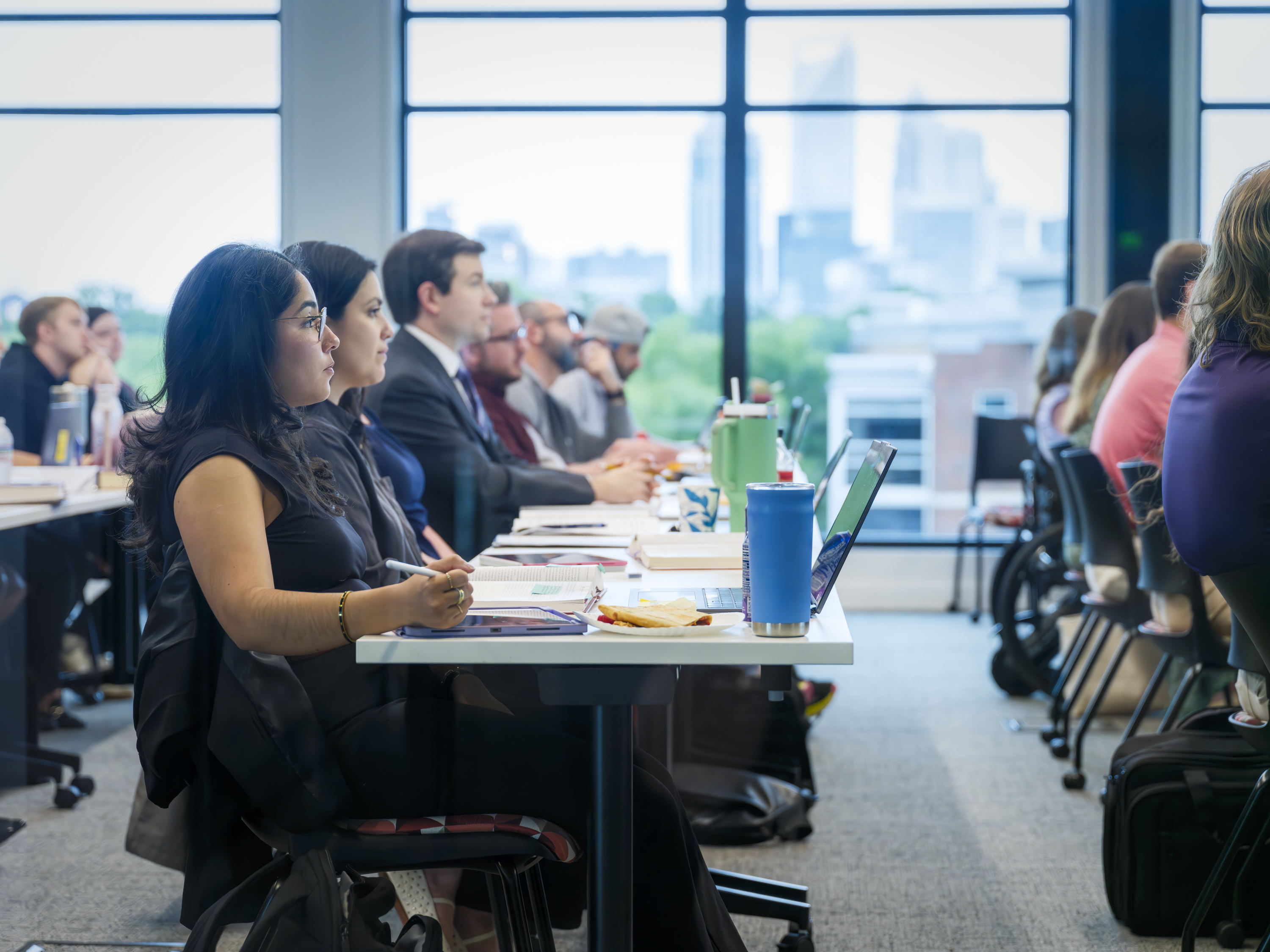 Classroom scene at Elon Law Flex Program, a part-time option at one of the top law schools in Charlotte. Students are in class with the Charlotte skyline seen through windows in the background.