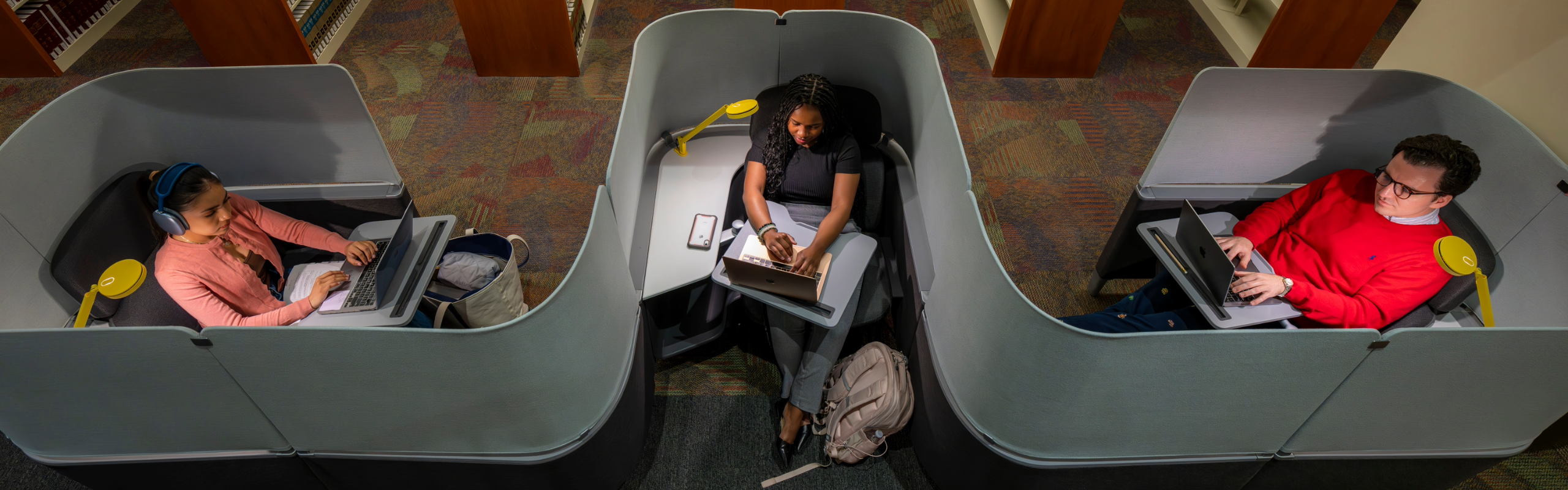 Three students study in carels inside Elon Law Library. PreLaw Magazine names Elon Law is one of the best law schools in NC for practical training.