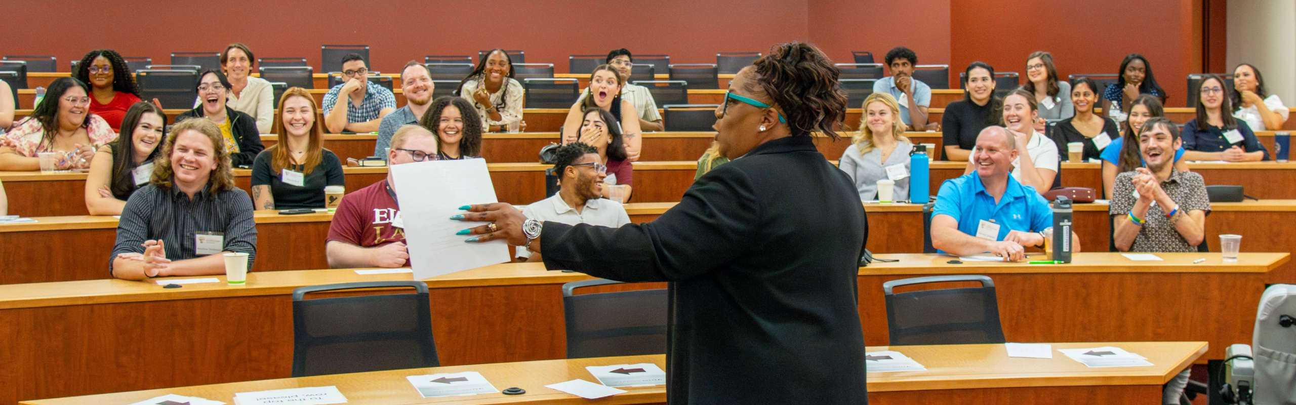 A professor is seen from behind lecturing as a large class of students laughs and reacts. PreLaw Magazine names Elon Law is one of the best law schools in NC for practical training.