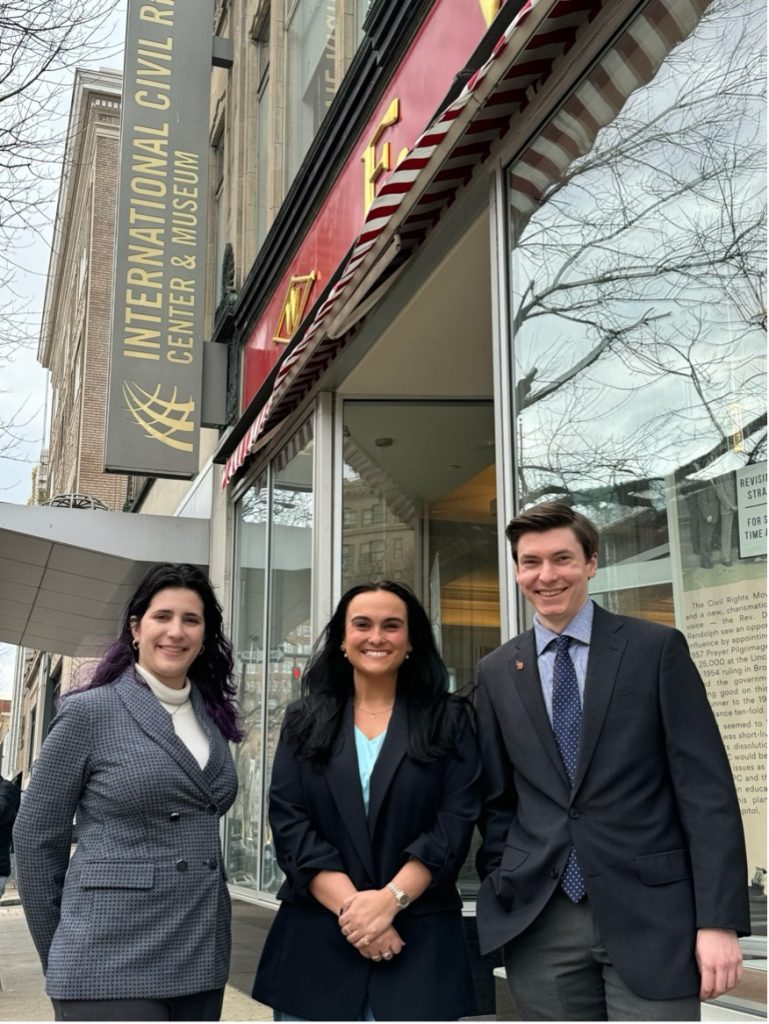 Three professionally dressed law students in front of the International Civil Rights Museum in Greensboro.