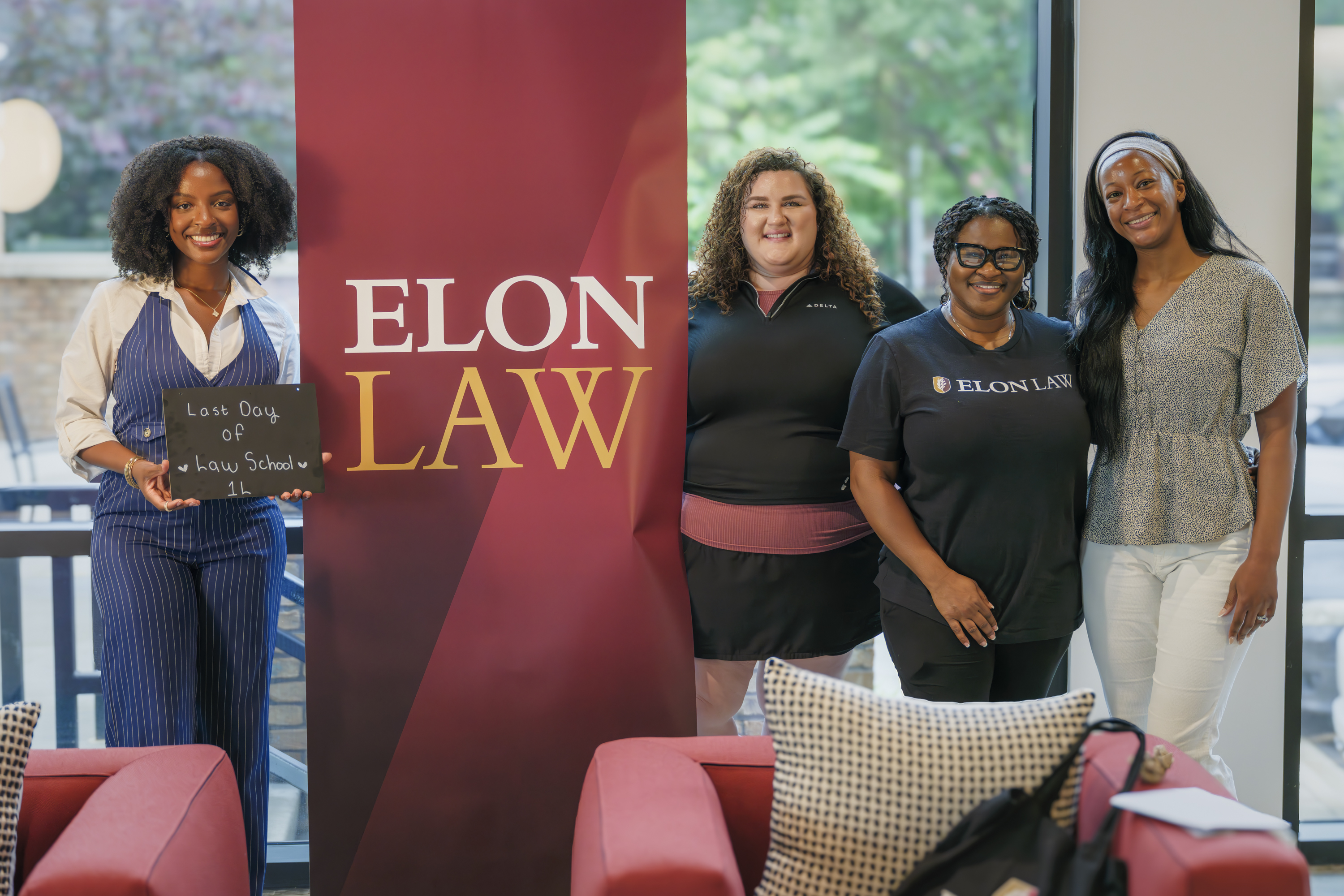 Students around a maroon Elon Law banner. Elon Law is one of the best law schools in nc for practical training and offers law school in Charlotte.
