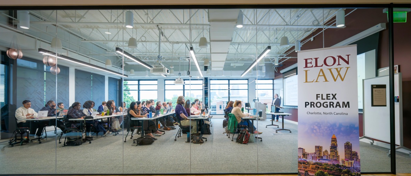 Wide shot of a large, windowed classroom overlooking the Charlotte skyline. A banner says Elon Law Flex Program. Attend part-time law school in Charlotte through the Elon Law Flex Program.
