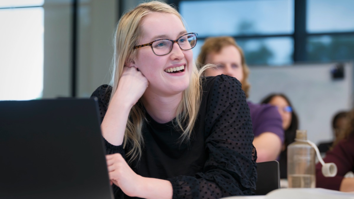 A female law student smiling during a class. Elon Law is one of the best law schools in NC for practical skills and offers law school in Charlotte.