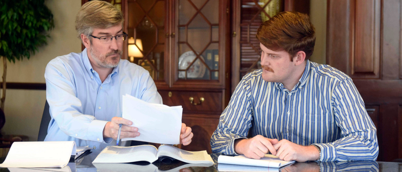An Elon Law student in residency with a supervisor reviewing documents at a conference table. 