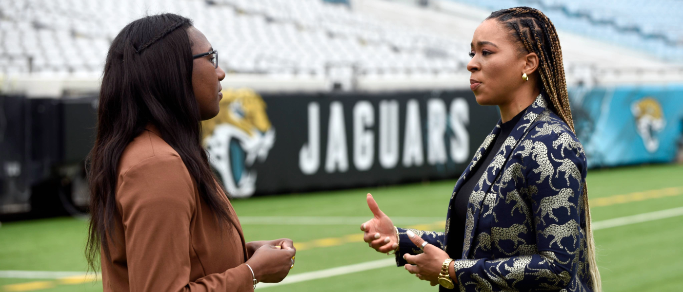 Kyra Auguste L'24 and her residency supervisor with the Jacksonville Jaguars on the NFL franchise's field